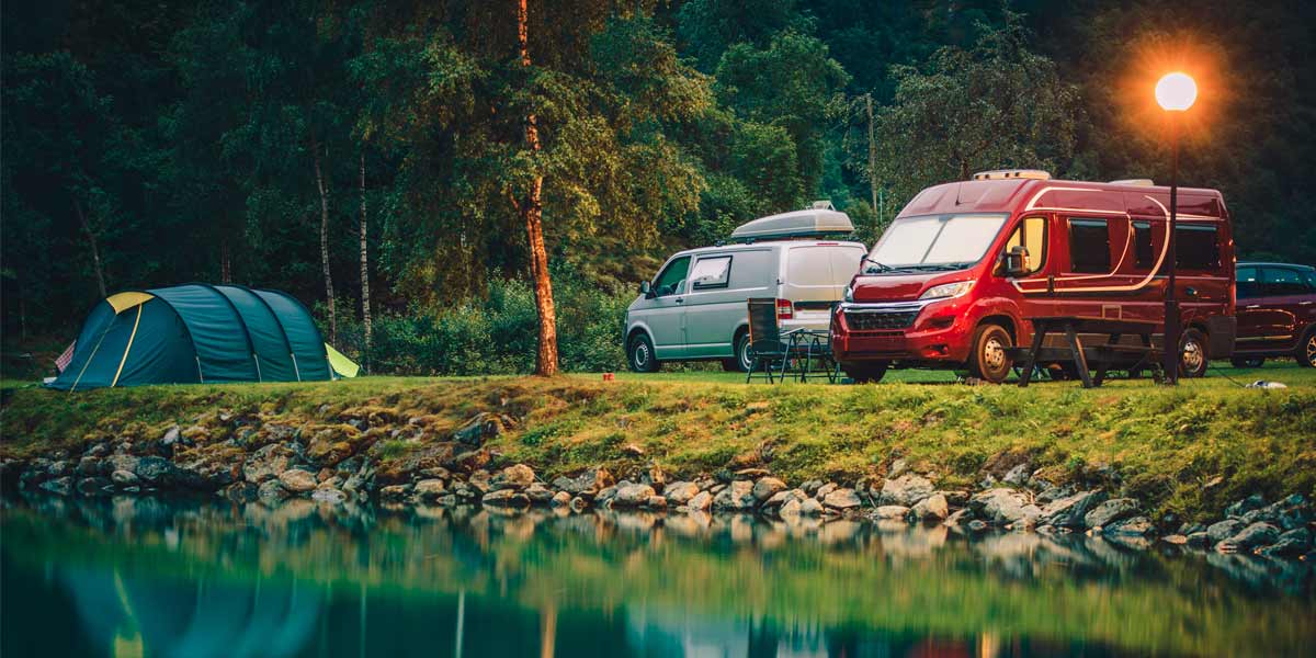 Campervans-and-tent Campervans and a tent beside a lake