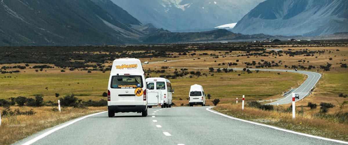 Several Campervans Driving on a Scenic Road Towards the Mountains