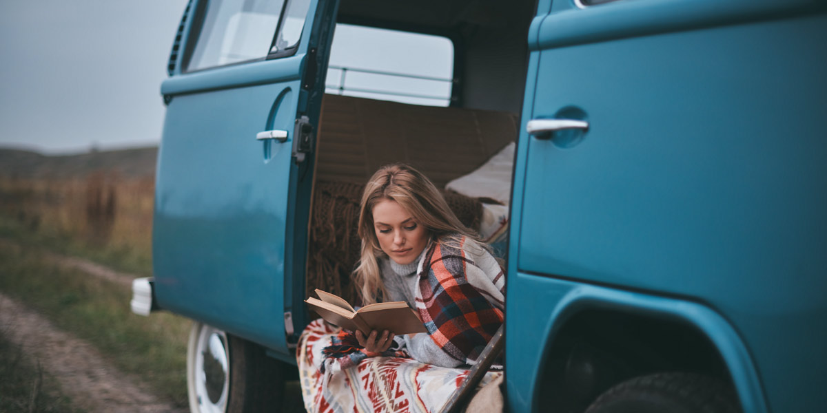 Woman reading a book in her classic VW campervan