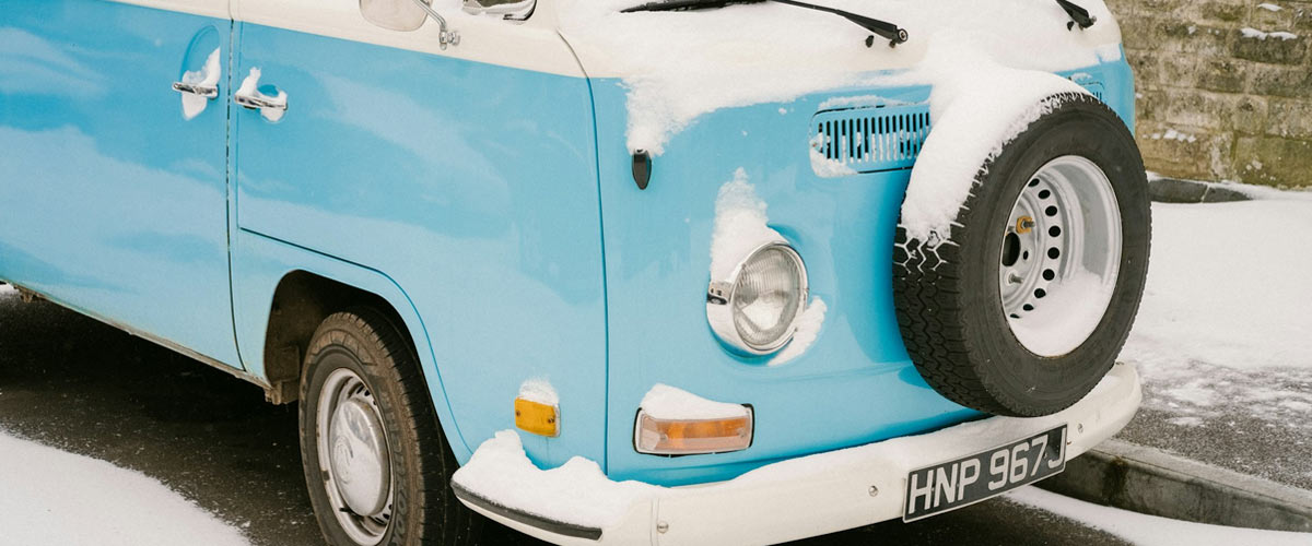 A blue VW T2 Bay camper parked on the road in the snow