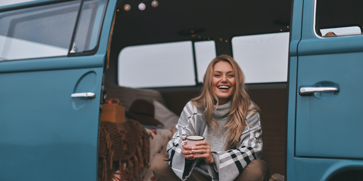 Happy-woman-sat-inside-a-classic-VW-camper Happy woman sat inside a classic VW T2 Campervan
