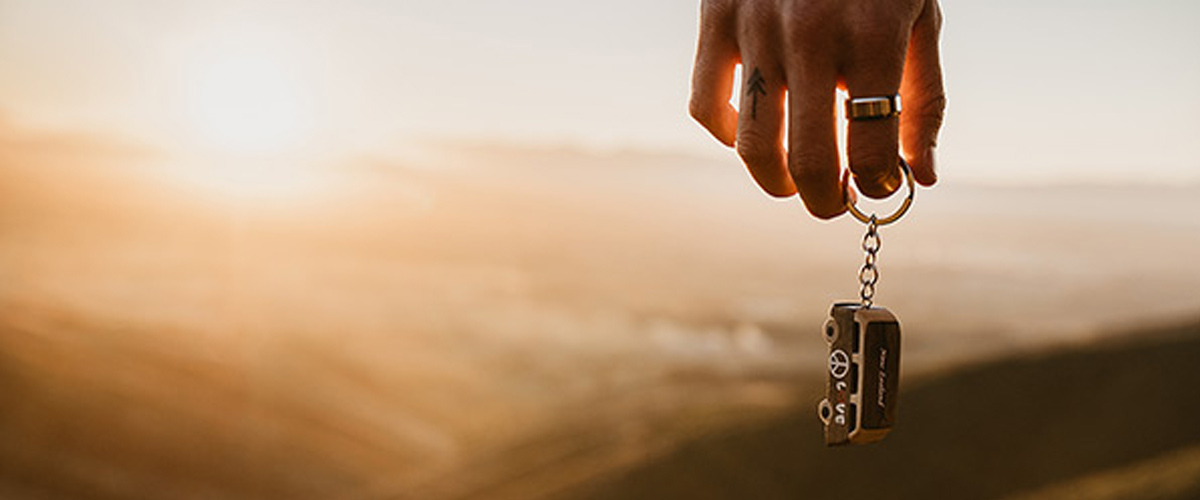 A hand holding a key with the sunset in the background