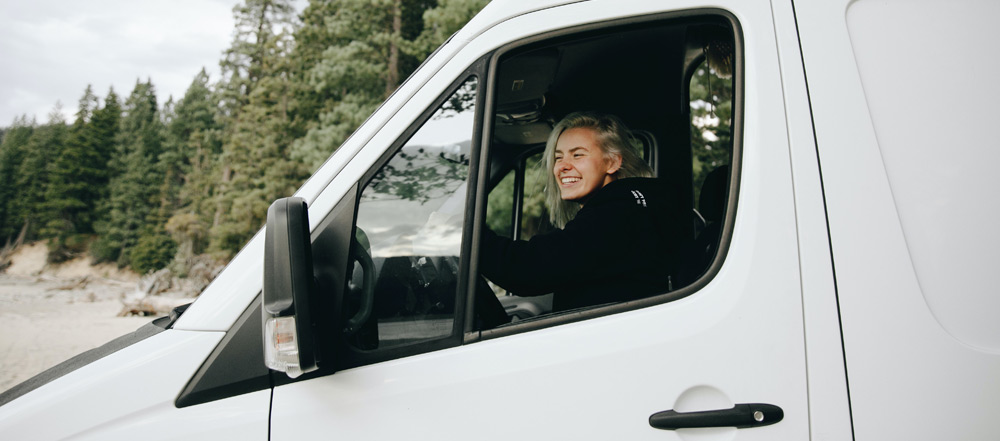 A woman driving a campervan with a smile on her face