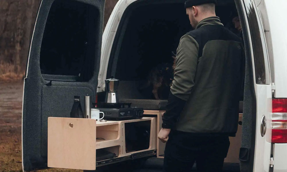 JKI25-Micro-Camper-Image-Header-1 A man making coffee in the back of his micro-camper