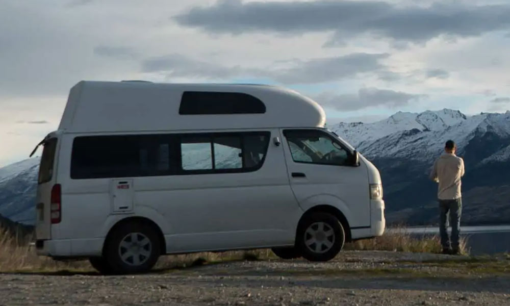 A white Toyota HiAce campervan parked up in the mountains