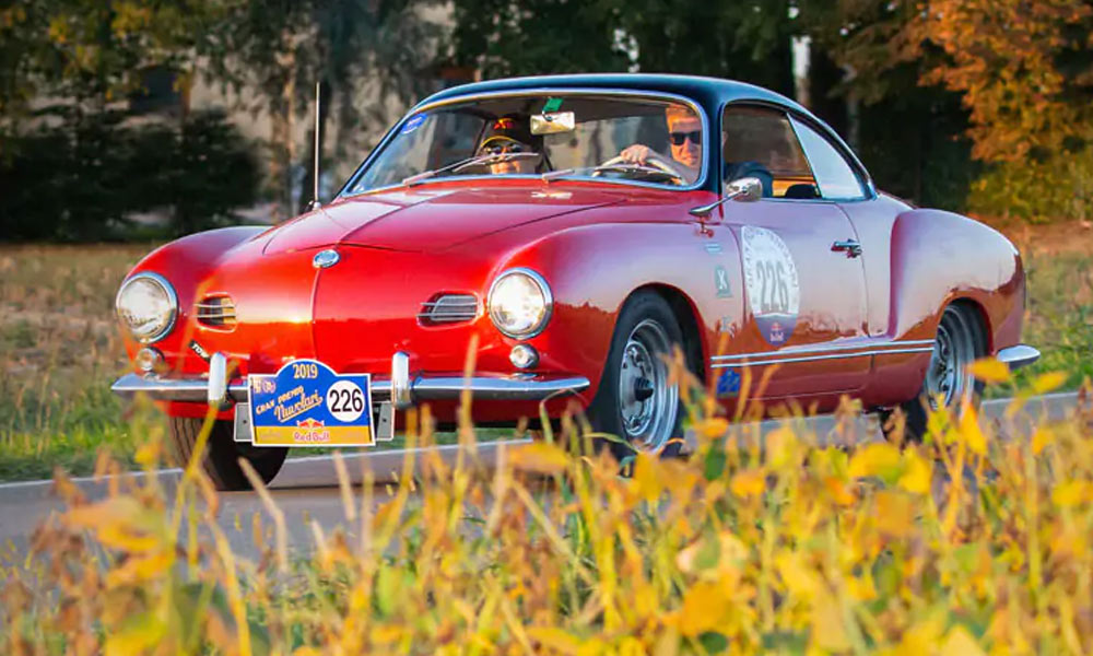 JKI25-VW-Classic-Car-Insurance-Header-1 A red and black VW Karmann Ghia driving on the Grand Prima Nuvolari