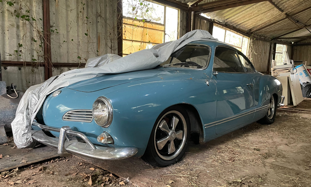 Excess-Protection-Image-for-Just-Kampers-Insurance A blue VW Karmann Ghia half covered inside a barn