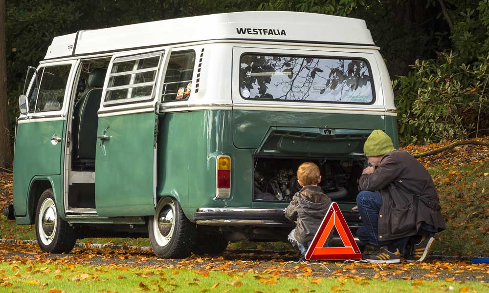 JKI25-Breakdown-Cover-Image-Header-1 A father and son looking at the engine of a VW T2 Bay camper, with a warning triangle set up behind the camper