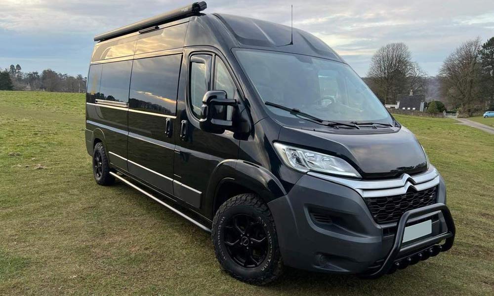 JKI25-Citroen-Relay-Image-Header-1 A black Citroën Relay which has been turned into a camper with an awning and extra windows