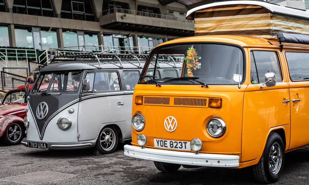 VW T2 Insurance Header Image for Just Kampers Insurance A pair of VW T2s on display at a VW show - a grey T2 Split and an orange T2 Bay