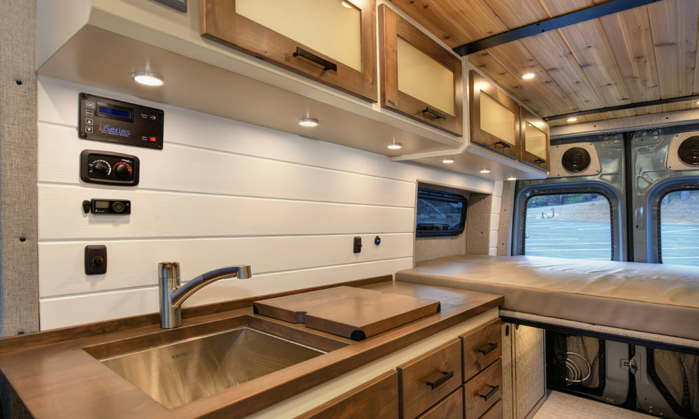 Contents-Cover-Header-Image-2.0-for-Just-Kampers-Insurance An image showing the inside of a campervan with appliances, speakers, and a sink