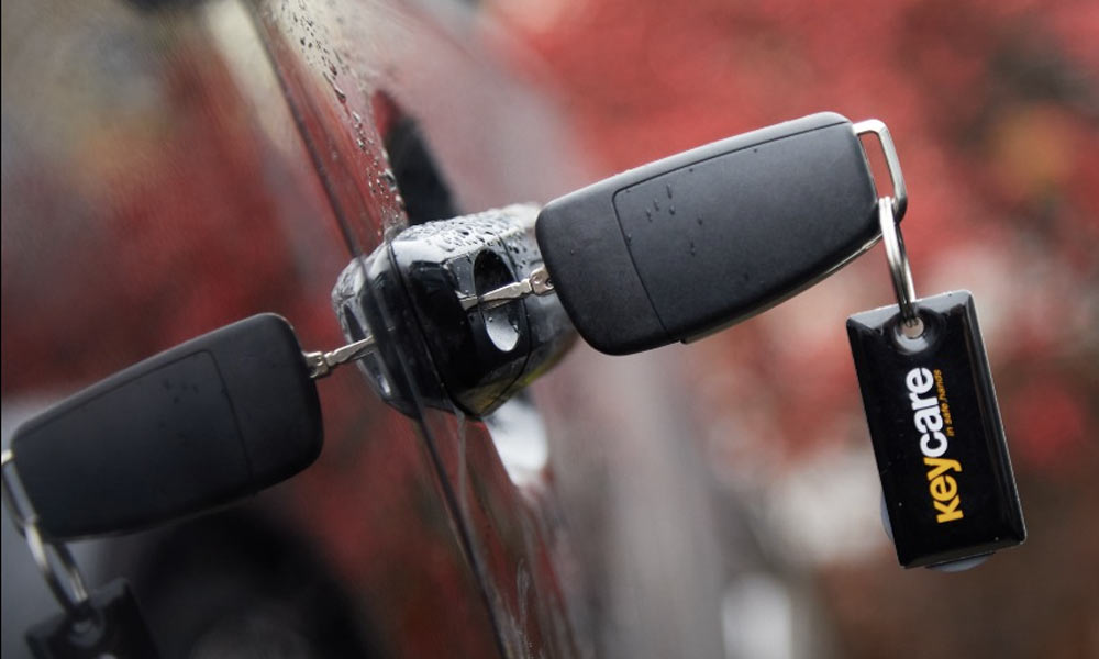 Key-Care-Header-Image-Just-Kampers-Insurance A key in a car door, display ing a Key Care keyring fob
