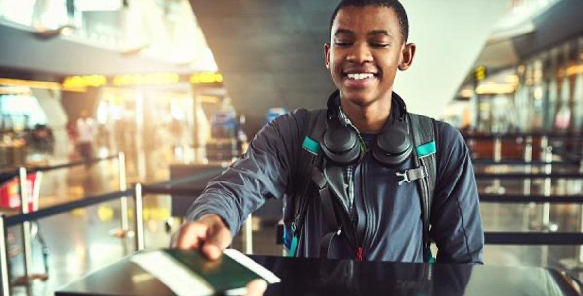A young man smiling as he's handing over his passport and ID documents