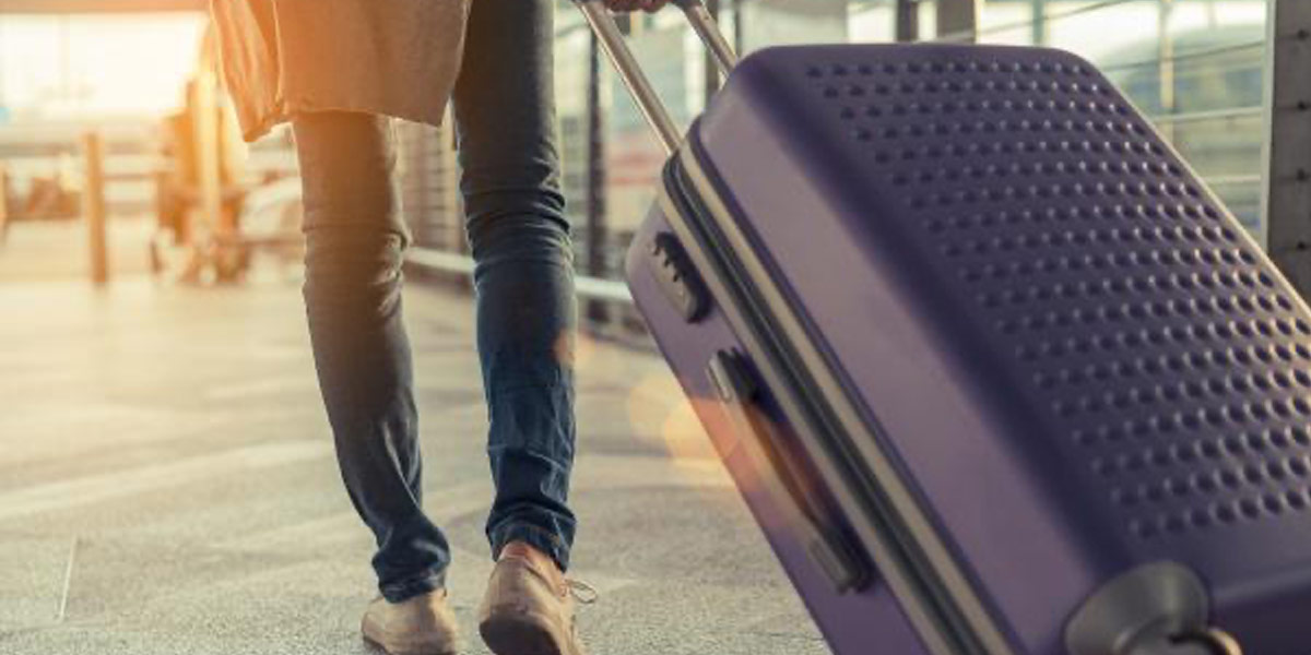 A purple suitcase being pulled along the pavement
