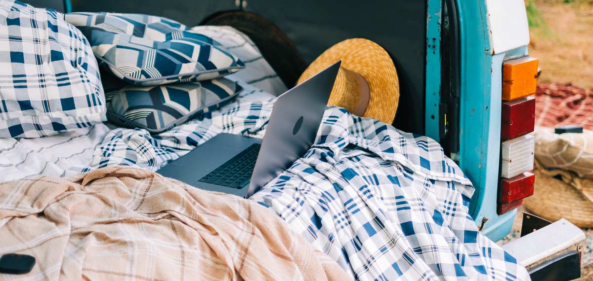 A laptop on some blankets in a campervan