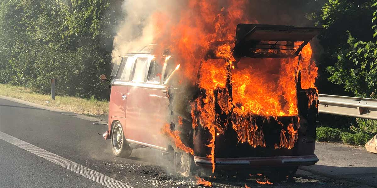 Classic VW Camper engulfed in flames at the side of the road