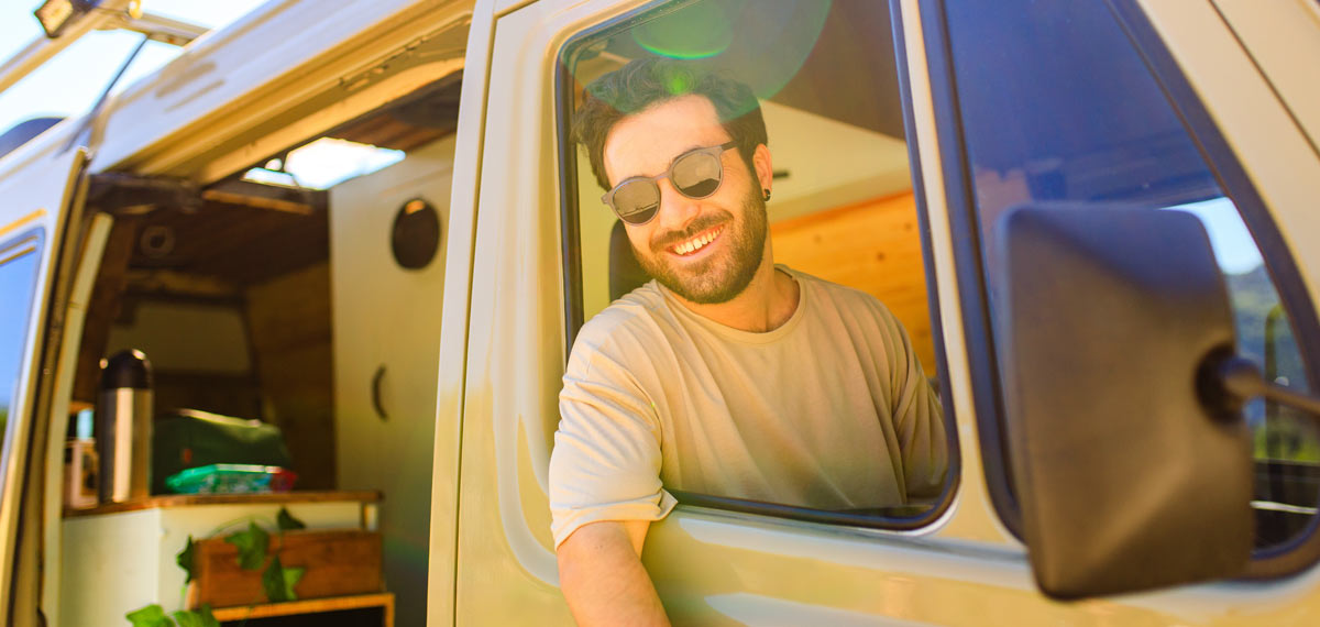 Man smiling from his converted campervan