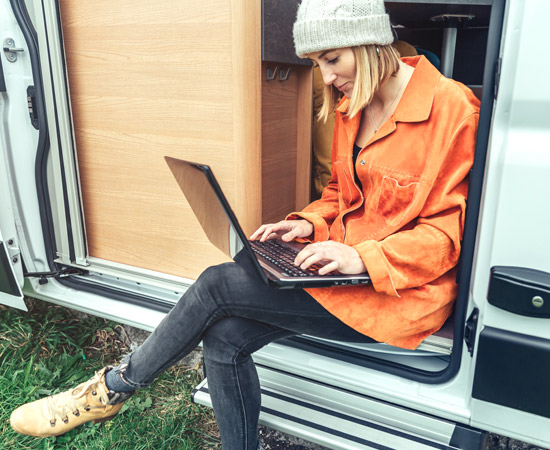Woman sitting in her motorhome using a laptop