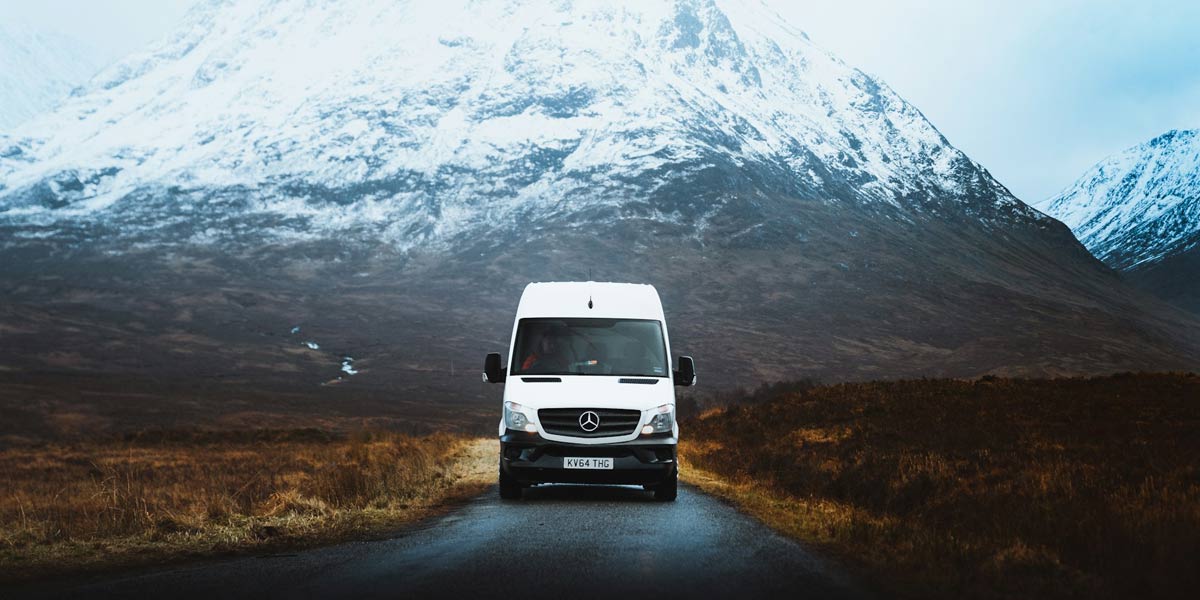 Campervan driving in front of a snowy mountain