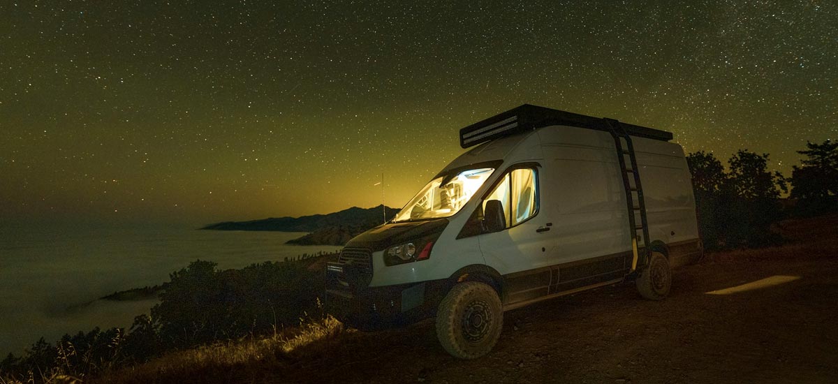 Converted campervan parked at the side of the road under the stars