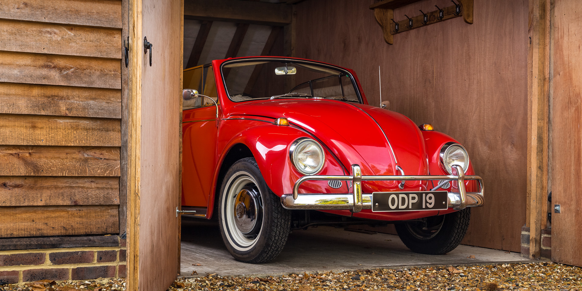 A red VW Beetle Cabriolet parked inside a wood-fronted garage