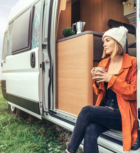 Vanlifer looking out of her van drinking a coffee