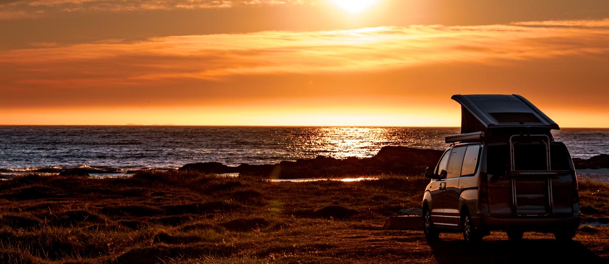 Converted camper by the ocean at sunset