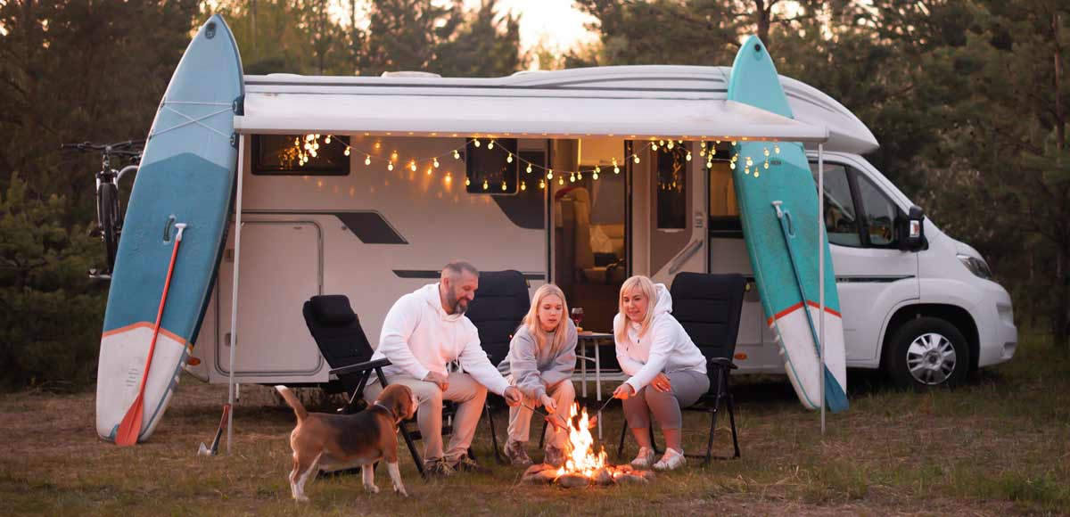 Family cooks on an open campfire by their motorhome