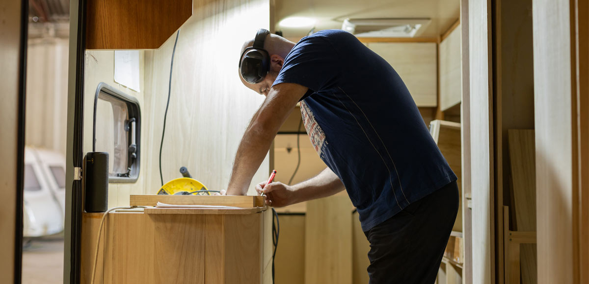Self built campervan owner installing kitchen cabinets