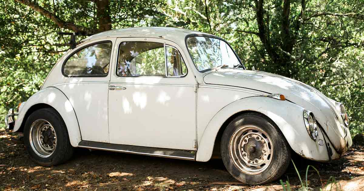 White VW Beetle parked on a dirt road 